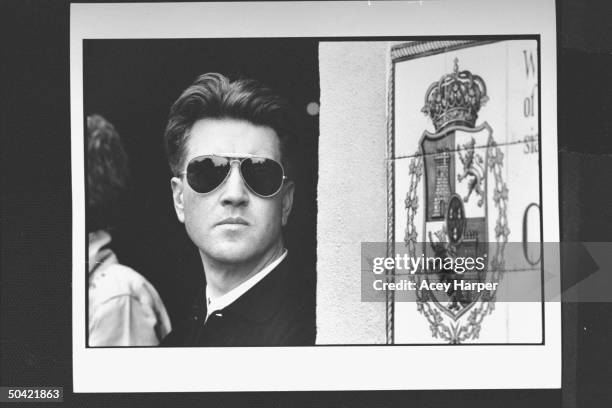 Movie director David Lynch, wearing aviator-style sunglasses while standing in doorway w. Coat of arms, on location during filming of movie Wild at...