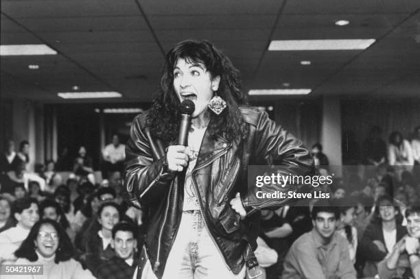 Commercial producer and comedienne Suzi Landolphi, in Langlitz-style leather jacket, w. Microphone giving her humorous lecture on AIDS & other...