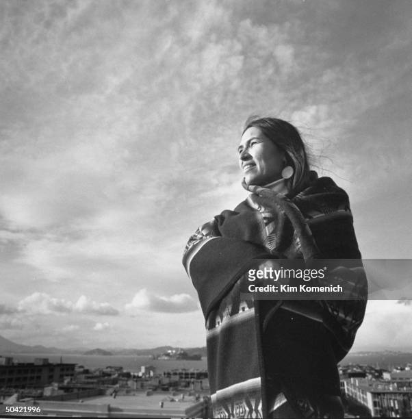 Actress/American Indian activist Sacheen Littlefeather wrapped in an Indian blanket outside w. Bay area in bkgrd. As she poses on rooftop.