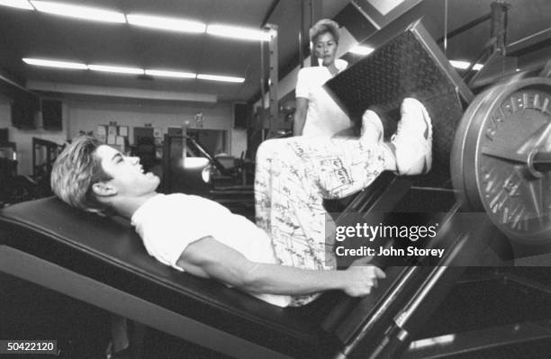 Teen actor Mark Paul Gosselaar working out on weight machine while mother Paula watches, Oakwood Health Club.