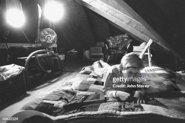 Teen actor Mark Paul Gosselaar studying on bed in his bedroom loft above family garage.