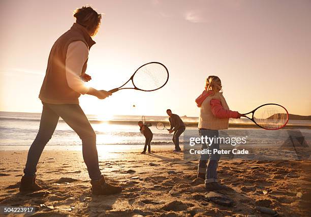 family playing tennis on beach at sunset - 4 people playing games stock-fotos und bilder