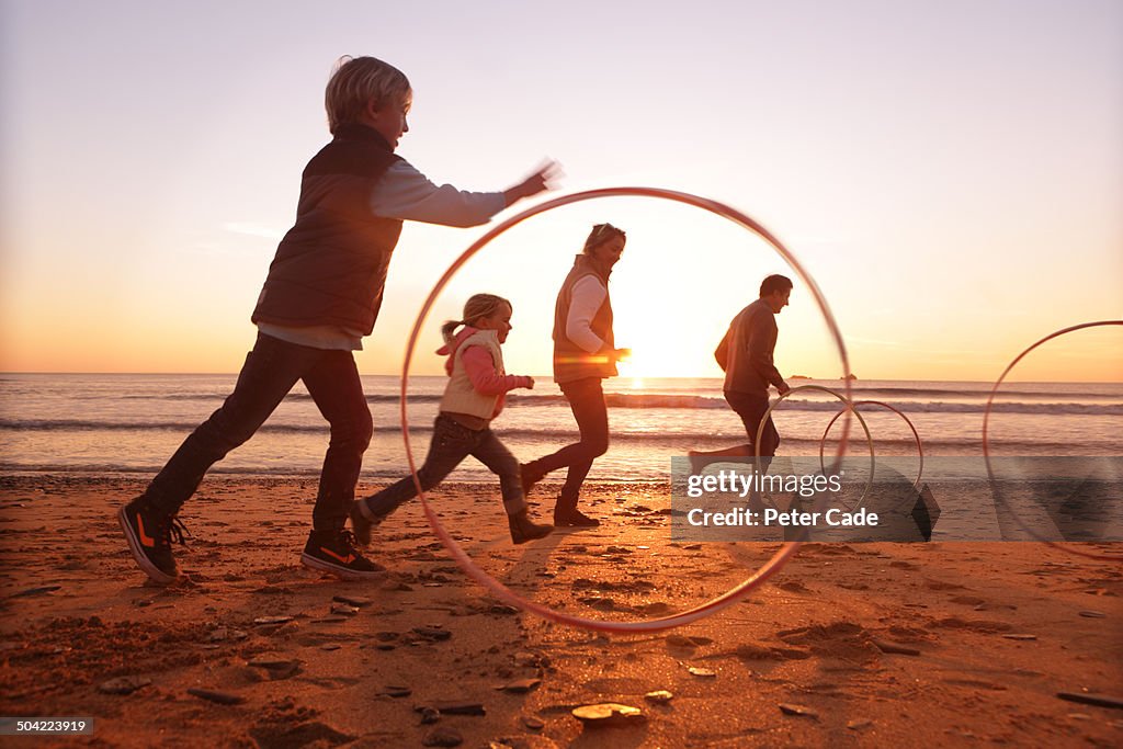 Family playing with hoops on beach at sunset