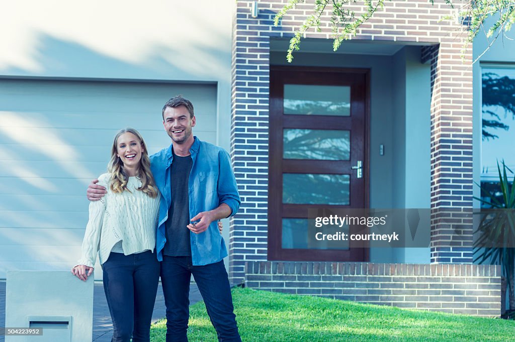 Couple standing in front of their new home.