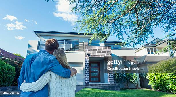 couple standing in front of their new home. - house of ogan stockfoto's en -beelden