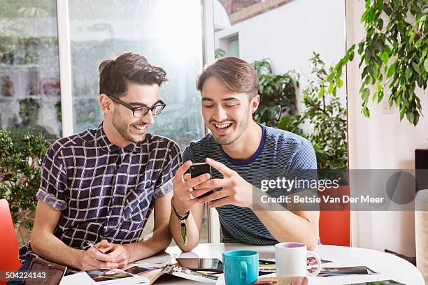 gay couple working from home,checking messages. - rumor stockfoto's en -beelden