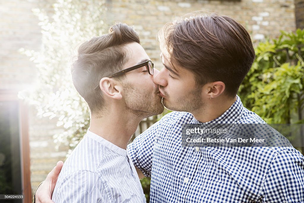 Gay couple kissing in garden.
