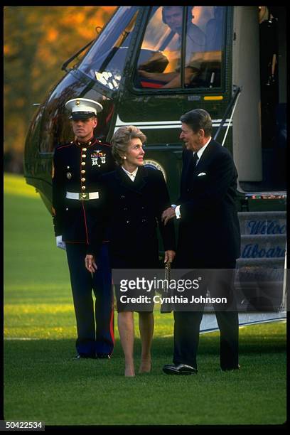 Pres. & Nancy Reagan returning to WH, standing in front of guard-attended Marine One copter.