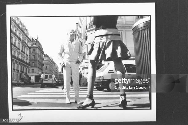 Fashion designer Andre Courreges who created the first miniskirt fashions 25 yrs. Ago, admiring model wearing one of his latest miniskirt creations...