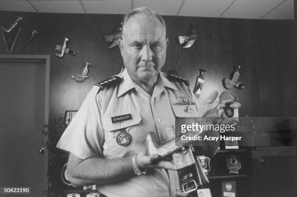 Army Gen. Norman Schwarzkopf, Cmdr-in-Chief of US Army Central Command, wearing short-sleeved army shirt, holding up Khanjar dagger in front of wall...