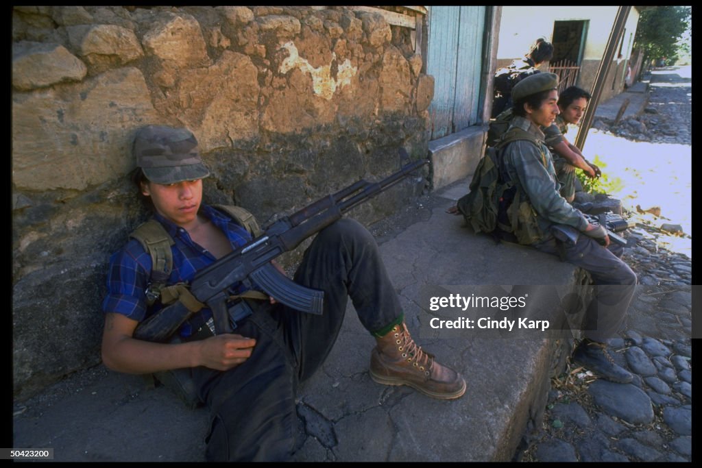 Youthful FMLN guerrillas sitting by wall