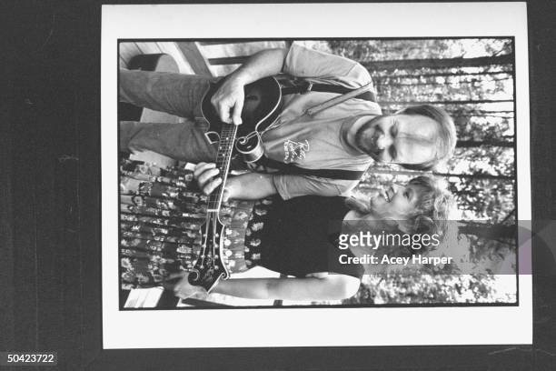 Country singer Patty Loveless posing w. Her husband, record producer Emory Gordy, Jr. Who is playing a mandolin on porch at home.