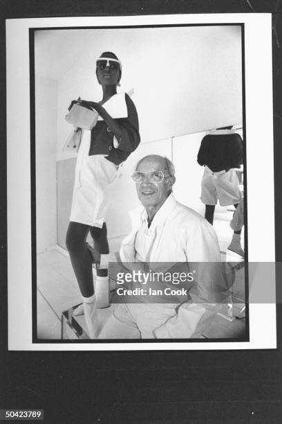 Fashion designer Andre Courreges posing w. Black model and sporting a pair of white rimmed sunglasses, as she poses in white shorts w. Flamboyant...