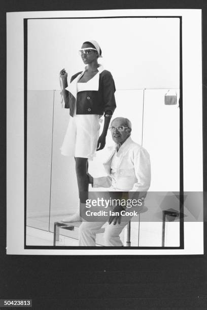 Fashion designer Andre Courreges posing w. Black model as she poses in white shorts w. Flamboyant short jacket, accented w. Famous white, low-top...