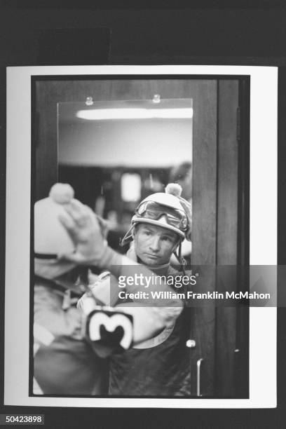 Racing jockey Pat Day adjusting riding helmet on his head as he looks at mirror in jockey room at Keeneland Race Track.