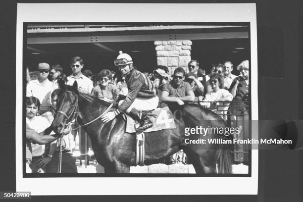 Jockey Pat Day wearing his racing silks as he sits on race horse in the walking ring as spectators look on from the fence before race at Keeneland...