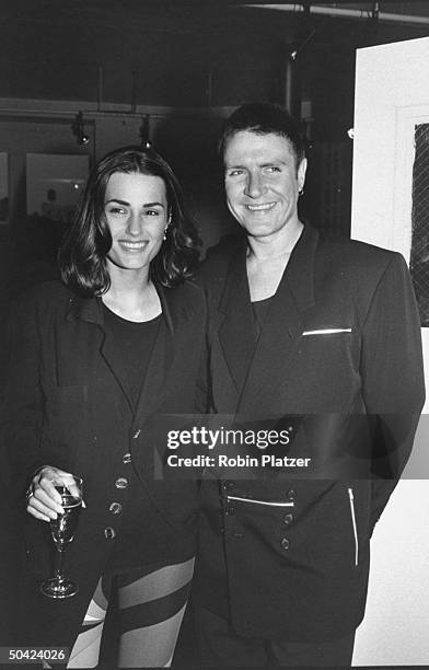 Singer Simon LeBon standing close to his wife Yasmin, who is dressed in Pucci-style leggings at book party.