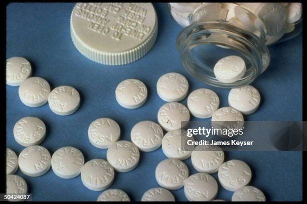 Closeup of aspirin tablets spilling out of plastic bottle, used in story re aspirin's ability to protect people against stroke.