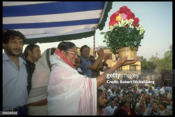 Awami League ldr. Sheik Hasina Wazed on stump, holding flower pot , during crowded election campaign rally.