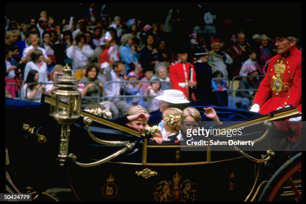 Peter Phillips riding with unidentified children in royal carriage along fan-lined route to church wedding of England's Prince Andrew to Sarah...