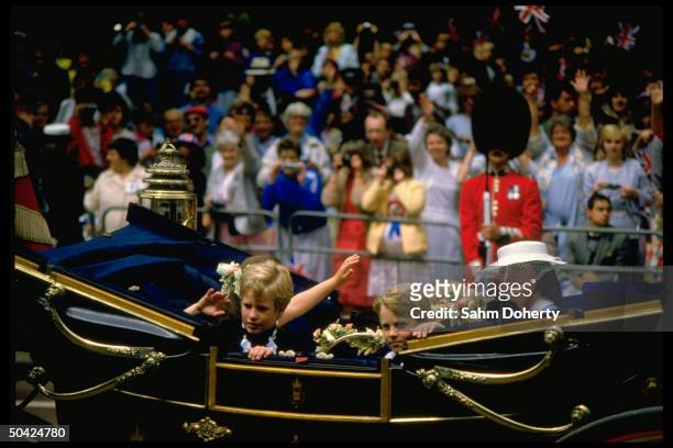 Peter Phillips riding with unidentified children in royal carriage along fan-lined route to church wedding of England's Prince Andrew to Sarah...
