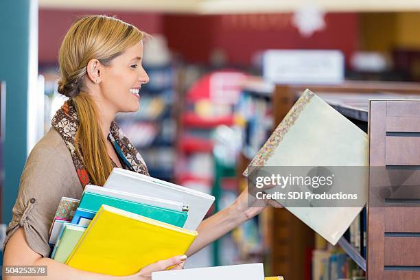librarian putting books away in children's section of public library - putting book on shelf stock pictures, royalty-free photos & images
