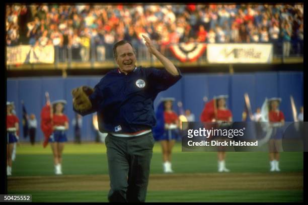 Pres. Bush indulging in high jinks, displaying great gusto, poised w. Mitt, throwing out opening ball at Rangers baseball game.