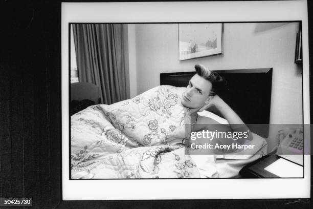 Rap singer Vanilla Ice posing in bed under the covers in hotel room.