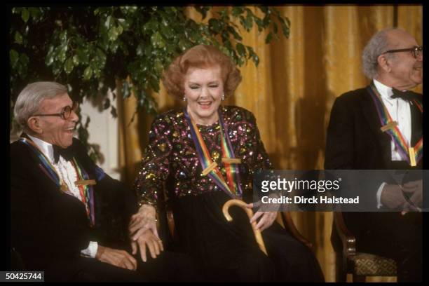 Kennedy Center honorees, actress Myrna Loy sitting w. George Burns , & Alexander Schneider, laughing after receiving award.