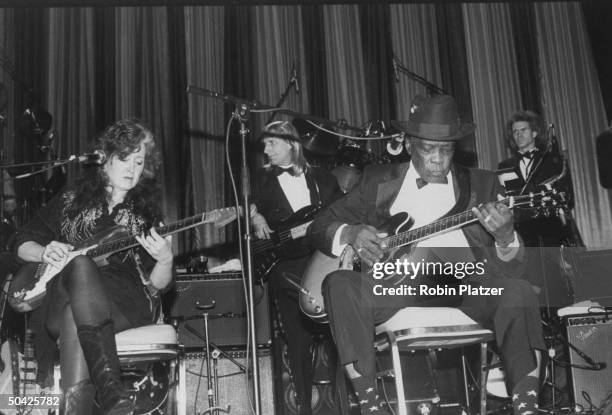 Blues singer John Lee Hooker dueting w. Bonnie Raitt; at Rock & Roll Hall of Fame dinner w. Other musicians in bkgrd.