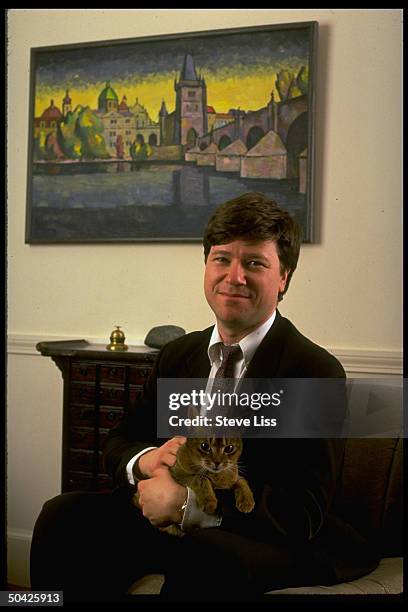 Harvard economist Jeffrey Sachs, holding cat, framed by colorful ptg.