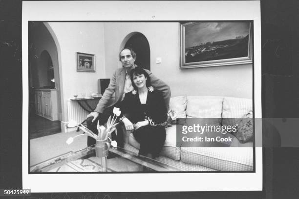 Author Philip Roth posing on couch w. His wife actress Claire Bloom in living room at home.