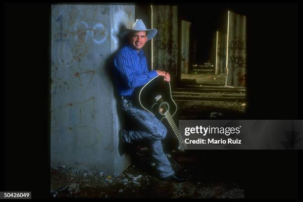 Singer Garth Brooks wearing cowboy hat and holding black acoustic guitar.