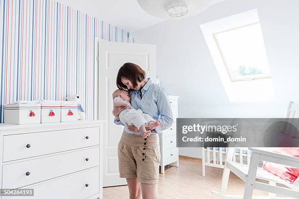 mother holding and cuddling little baby boy tenderly, baby's room - nursery bedroom stock pictures, royalty-free photos & images