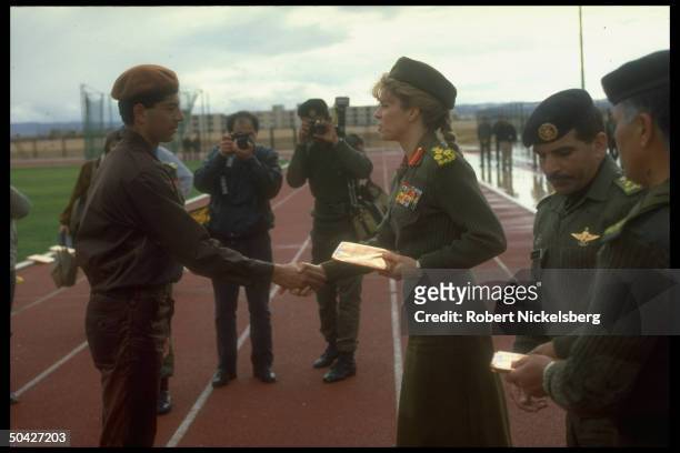 Queen Noor, jaunty in her mil. Uniform, shaking soldier's hand, w. Officers & photographers, at People's Army reserve unit graduation .