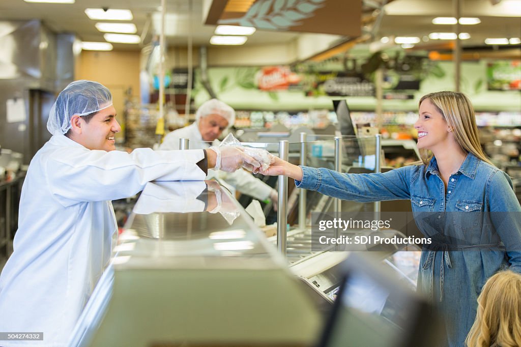 Butcher or deli manager assisting customer in local supermarket