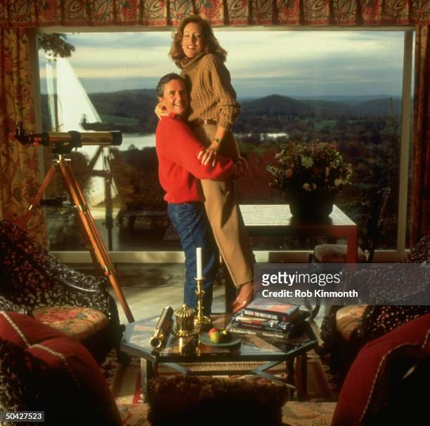 American Express CEO James Robinson lifting wife Linda in the livingroom of their farmhouse.