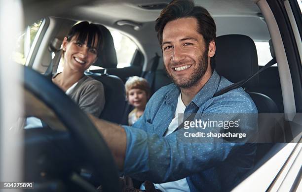 we love our family roadtrips - couple in car smiling stockfoto's en -beelden