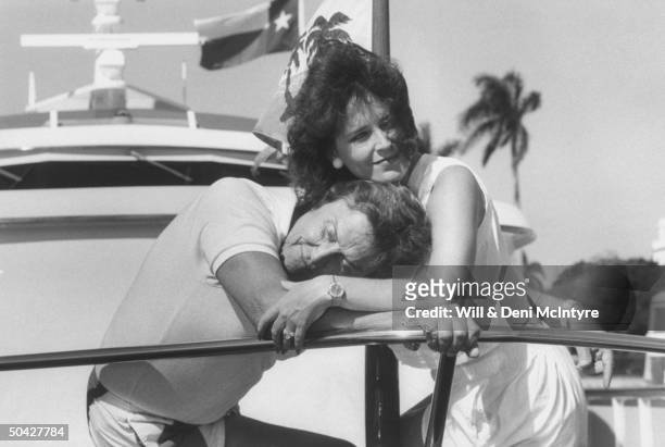 Singer, businessman Jimmy Dean cuddling w. His fiancee, singer Donna Meade, as they stand on the deck of his yacht.