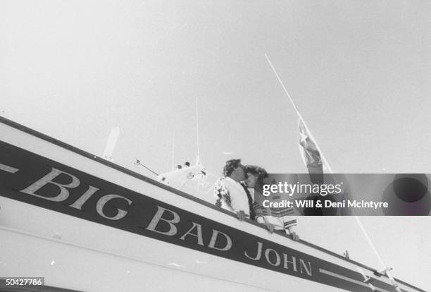 Singer, businessman Jimmy Dean kissing the forehead of his fiancee, singer Donna Meade, as they stand at the side rail of his yacht, Big Bad John.