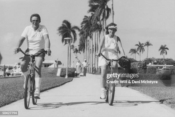 Singer, businessman Jimmy Dean w. His fiancee, singer Donna Meade, riding bicycles together on sidewalk.