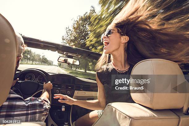 fröhliche frau, die spaß in cabriolet mit ihrem freund. - screaming happy in car stock-fotos und bilder