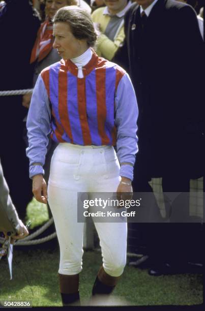 Princess Anne in racing outfit standing amongst others at benefit race.