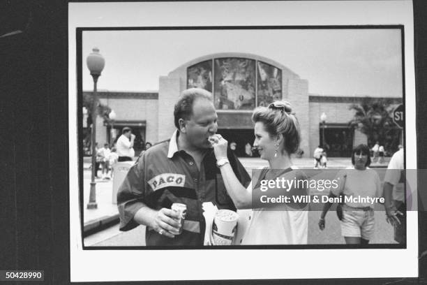 Farrell Gordon being fed popcorn by his fiancee Teri Thomas outside Universal Studios; Gordon worked undercover w. The FBI to help convict his...