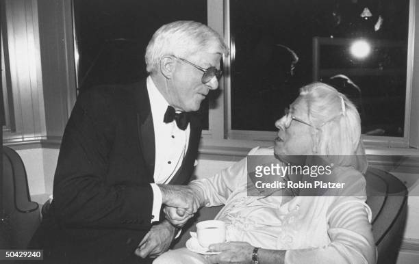 Personality Phil Donahue holding hands & chatting w. Madalyn Murray O'Hair, an Atheist who was the first guest to appear on his show, at a...