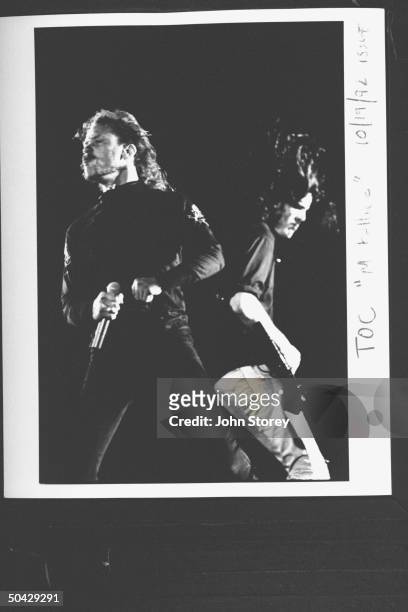James Hetfield, lead singer and rhythm guitarist for the rock group Metallica holding hand mike as he performs on stage next to stand-in guitarist...