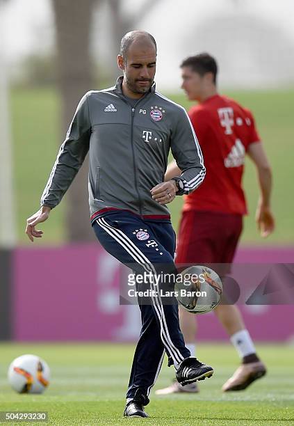 Head coach Josep Guardiola kicks a ball during a training session at day five of the Bayern Muenchen training camp at Aspire Academy on January 10,...