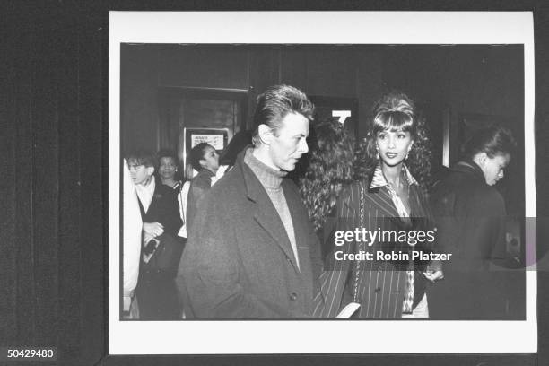 Rock star David Bowie arriving w. His model wife Iman at theater for a screening of the movie Malcolm X.