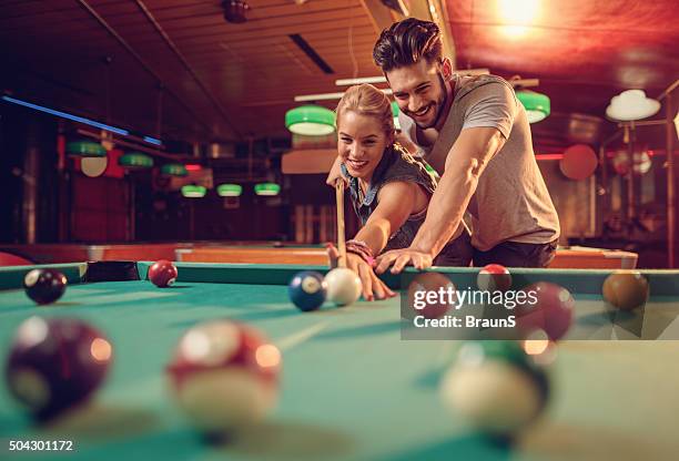 joven feliz pareja disfrutando juntos en un juego de billar. - billar deporte de taco fotografías e imágenes de stock
