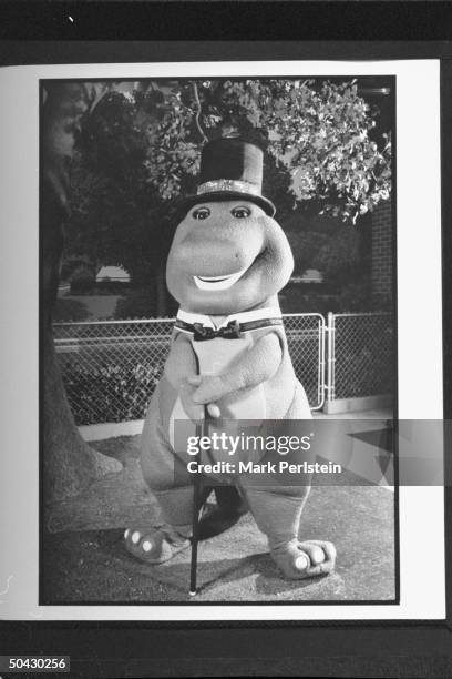 Barney the dinosaur wearing top hat & bow tie, holding cane while performing song & dance on the TV show Barney And Friends.